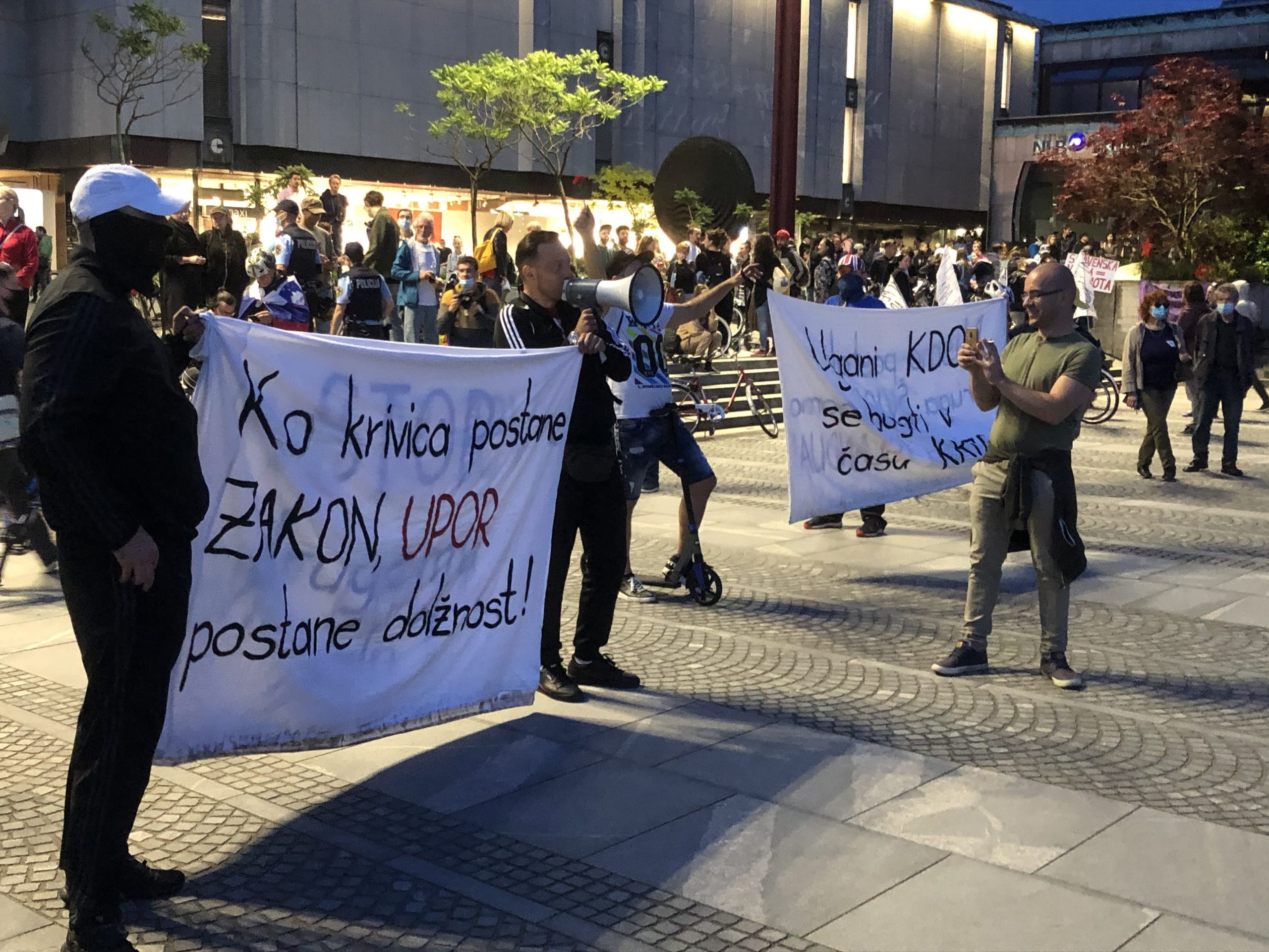 (VIDEO) Na protestih sinoči na meji spopada med policijo in demonstranti – Aretacija zaradi nošenja majice Smrt janšizmu, svoboda naroda – Protestnike na Aškerčevi pričkal hladen tuš, saj jih je nekdo oblival z vodo z balkona